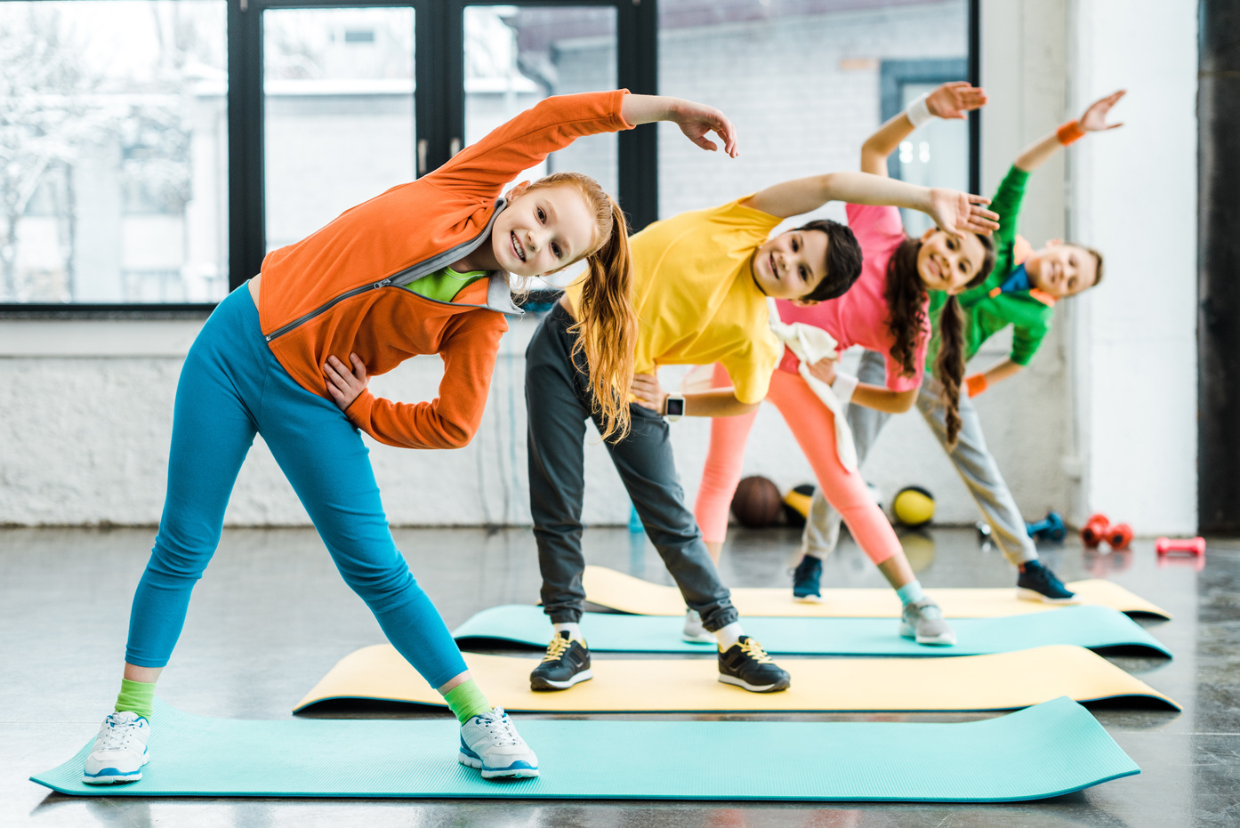 Smiling preteen kids doing sport exercise together